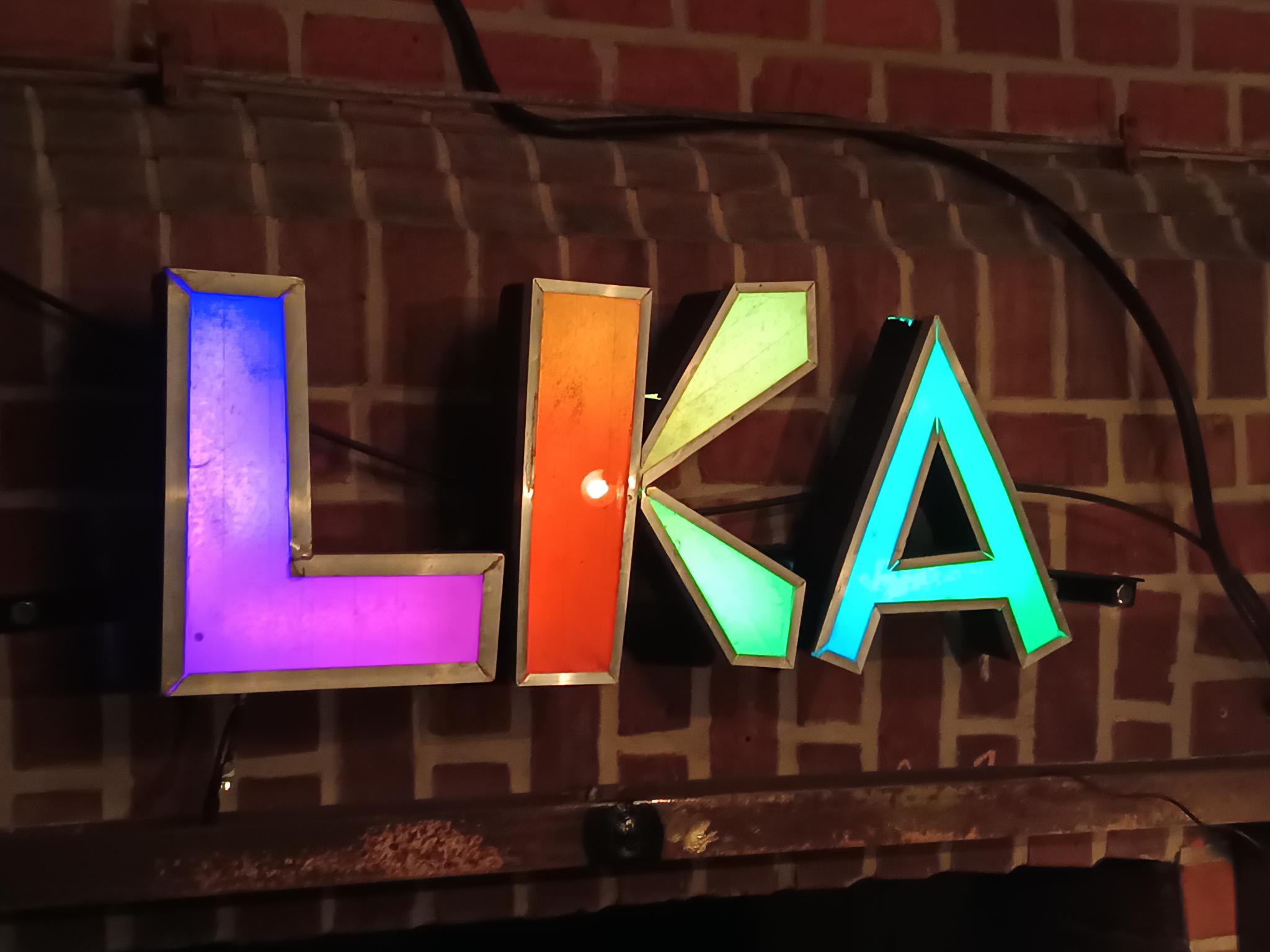 Schild des LKA über der Eingangstür. Das Schild ist mit einem bunten Farbverlauf beleuchtet. 